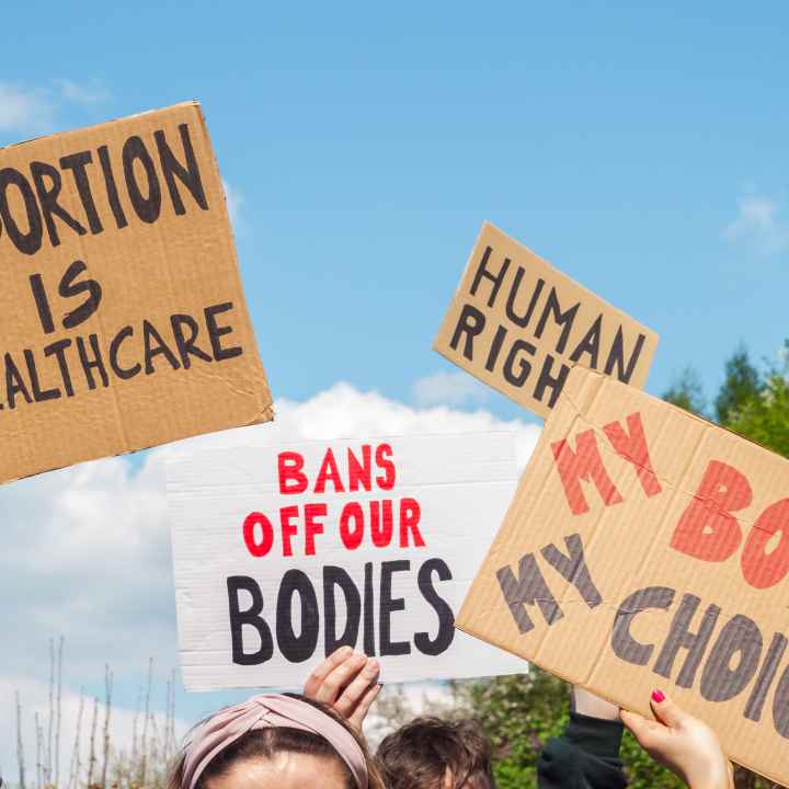 Protest signs for abortion that read "abortion is healthcare", "my body my choice," and "bans off our bodies"